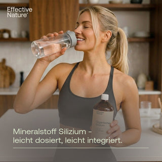 Frau trinkt aus Trinkflasche, hält Effective Nature Organisches Silizium Flasche in Küche