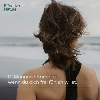 Frau von hinten am Meer, windiges Haar, schwarzes Top, Text: D-Mannose Komplex – wenn du dich frei fühlen willst.