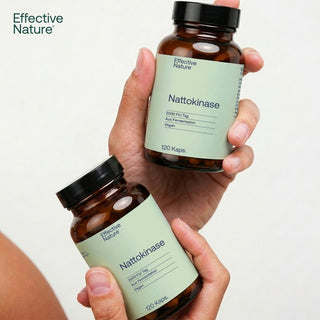 Zwei Glasflaschen Effective Nature Nattokinase 120 Kapseln, 2000 FU/Tag, vegan, in Händen gehalten