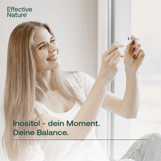Lächelnde Frau hält Inositol-Kapsel von Effective Nature ans Licht – Inositol dein Moment, deine Balance
