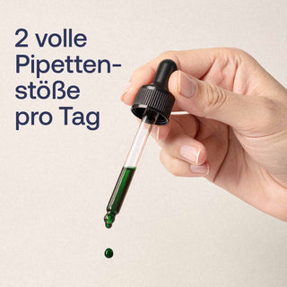 Hand hält Glaspipette mit grüner Fluessigkeit, ein Tropfen faellt ab, Text: 2 volle Pipettenstoeße pro Tag